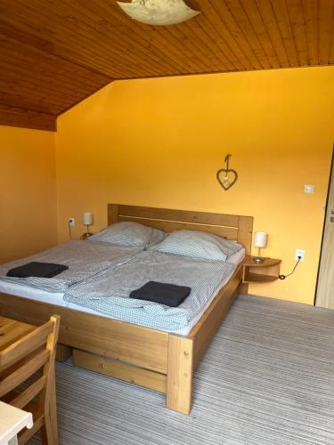 Ce lit se trouve dans une chambre dotée d'un mur jaune. dans l'établissement Chalupa pod Pustevnami, à Trojanovice