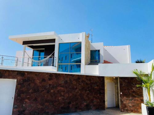 a house with blue windows and a stone wall at Fogo Boutique Hotel in São Filipe