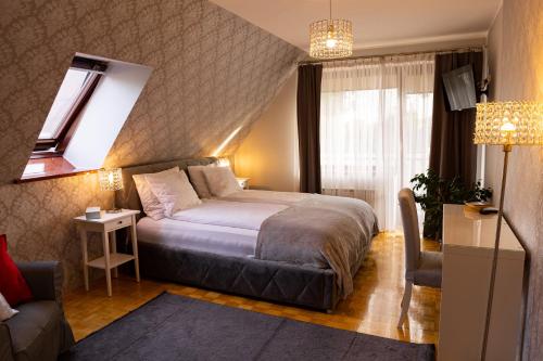 a bedroom with a bed and a couch and a window at Willa Biała Magnolia in Nowy Targ