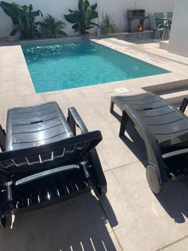 a pool with two chairs and a bench next to it at Maison Bella in Empuriabrava