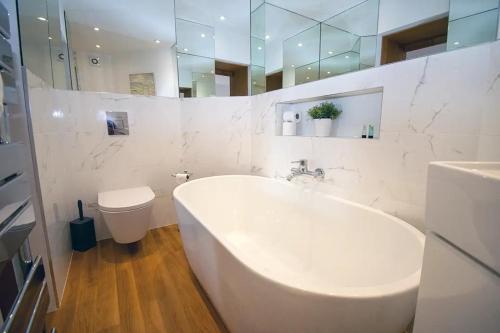 a white bathroom with a tub and a toilet at Seafront Cottage - The Nook in Cardiff