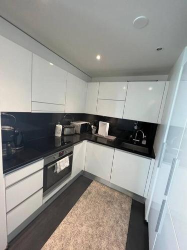 a kitchen with white cabinets and a black counter top at Kotimaailma - Tyylikäs kaksio keskustan tuntumassa in Helsinki