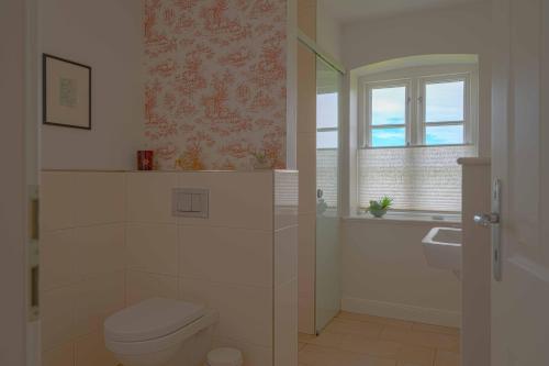 a bathroom with a toilet and a sink and a window at Ferienwohnung Rüm Hart in Hattstedtermarsch