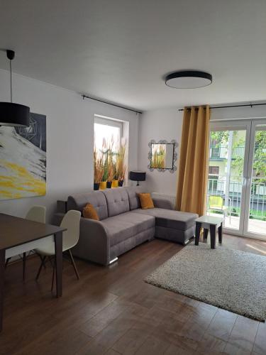 a living room with a couch and a table at Apartament w Bursztynowych Komnatach in Darłówko