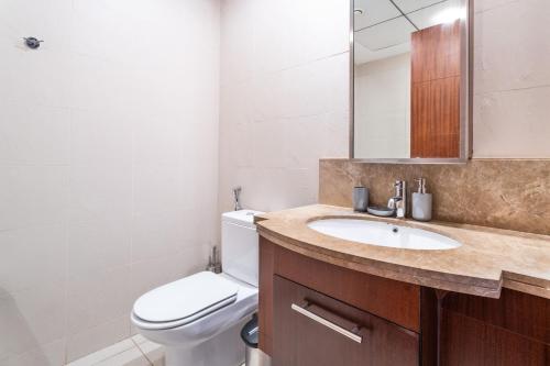 La salle de bains est pourvue de toilettes, d'un lavabo et d'un miroir. dans l'établissement Nasma Luxury Stays - Sophisticated Studio Apartment near Burj Khalifa, à Dubaï