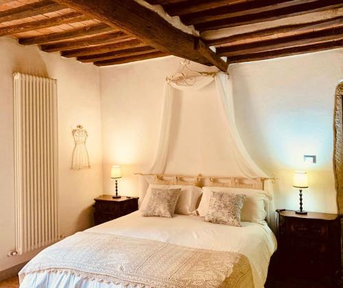 ein Schlafzimmer mit einem weißen Bett und zwei Nachttischen in der Unterkunft Casa il Cassero in Castiglion Fiorentino