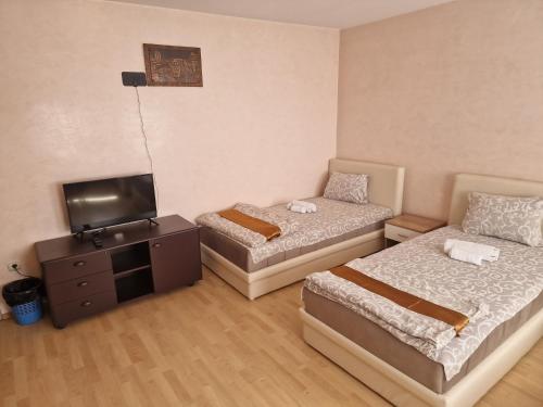 two beds in a room with a tv and a bedskirts at Hotel Saradis in Kruševac