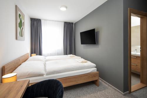 1 dormitorio con 1 cama y TV en la pared en Hotel Granit Smrekovica en Liptovská Osada