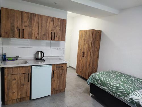 eine Küche mit Holzschränken und ein Bett in einem Zimmer in der Unterkunft Heidenheimer Zimmer in Heidenheim