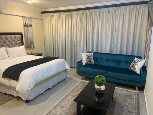 a bedroom with a bed and a blue couch at One & Only Bush Lodge in Bela-Bela