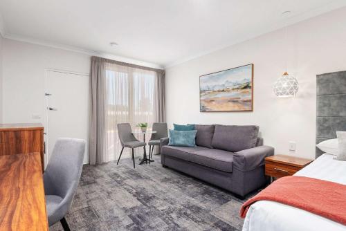a hotel room with a bed and a couch and a table at Comfort Inn Deakin Palms in Mildura