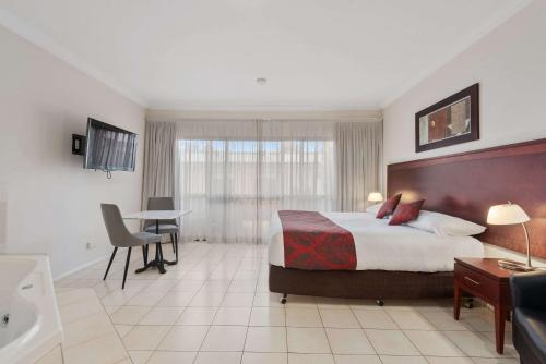 a hotel room with a bed and a desk at Comfort Inn Deakin Palms in Mildura
