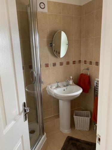 ein Bad mit einem Waschbecken und einer Dusche mit einem Spiegel in der Unterkunft An Mordros 15 Polkirt Heights in Mevagissey