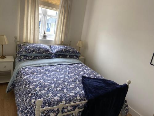 ein Schlafzimmer mit einem Bett mit blauer Decke und einem Fenster in der Unterkunft An Mordros 15 Polkirt Heights in Mevagissey