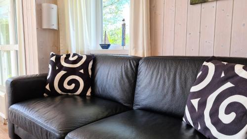 a black leather couch with two black and white pillows at Ferienhaus Strandoase in Brodersby