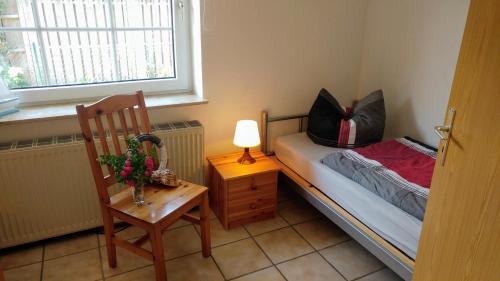 um pequeno quarto com uma pequena cama e uma cadeira em Ferienhaus zwischen Fjord und Meer em Maasholm