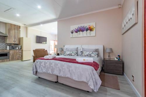 a bedroom with a large bed and a kitchen at RSA Lodge in Benoni