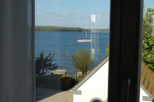 a sail boat on the water from a window at Ferienwohnung Großer Onkel Nr 1 in Maasholm