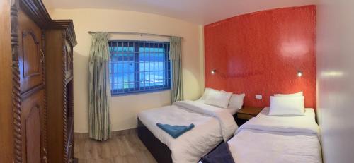 a small room with two beds and a window at The North Face Inn's Homestay in Pokhara