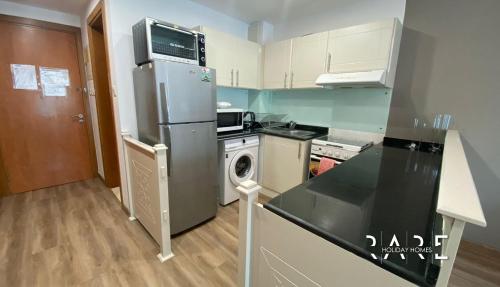 a kitchen with a refrigerator and a washing machine at RARE Holiday Homes - Deluxe Studio - Near City Center Mall - IMPZ - R2112 in Dubai