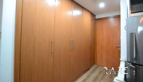 una fila de armarios de madera en una cocina en RARE Holiday Homes - Deluxe Studio - Near City Center Mall - IMPZ - R2112 en Dubái