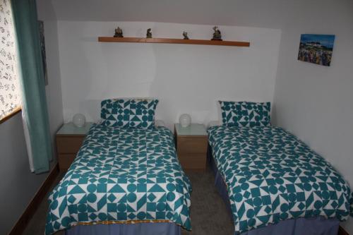 a bedroom with two beds with blue and white sheets at Beechwood B+B in Fort William