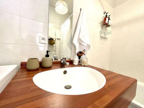 une salle de bain avec un lavabo blanc sur un comptoir en bois dans l'établissement L’azur - Centre ville & Lac, à Nantua