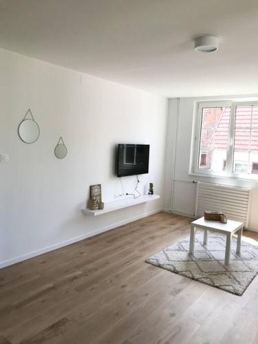 a white living room with a table and a tv at Gîte Niederbronn-les-Bains in Niederbronn-les-Bains
