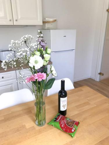 a bottle of wine and a vase of flowers on a table at Gîte Niederbronn-les-Bains in Niederbronn-les-Bains