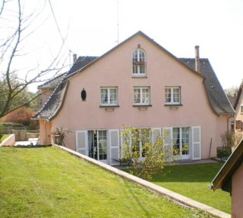 uma grande casa cor-de-rosa com um jardim verde em Gîte Niederbronn-les-Bains em Niederbronn-les-Bains