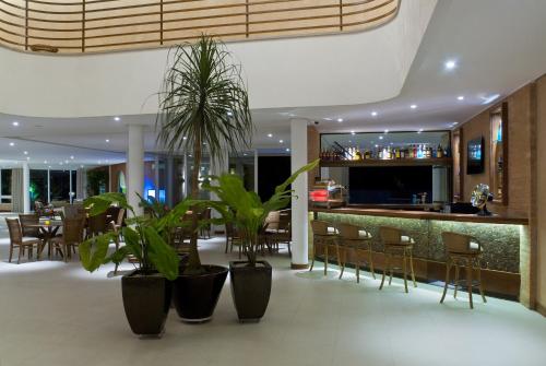 a restaurant with a bar with chairs and plants at Abayomi Hotel in Ilhabela