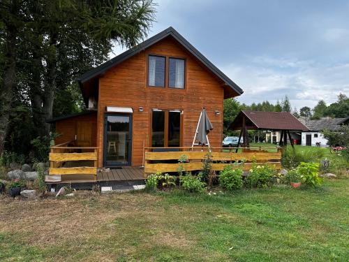 ein Holzhaus mit einer Veranda und einem Zaun in der Unterkunft Zamieszkaj na wsi blisko Warszawy in Borucza