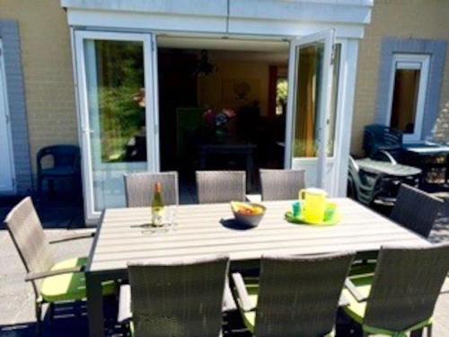 a table with chairs and a bottle of wine on it at Groot vakantiehuis direct aan het Zeeuwse strand in Kamperland