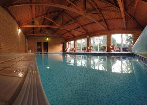 a large indoor swimming pool with a wooden ceiling at The Grove Cromer in Cromer