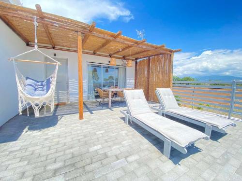 a patio with a hammock and a table and chairs at Boho Bliss Seaview Detached House in Análipsis