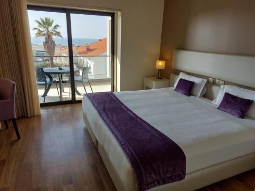 a bedroom with a large bed and a balcony at Hotel Monte Lírio in Espinho