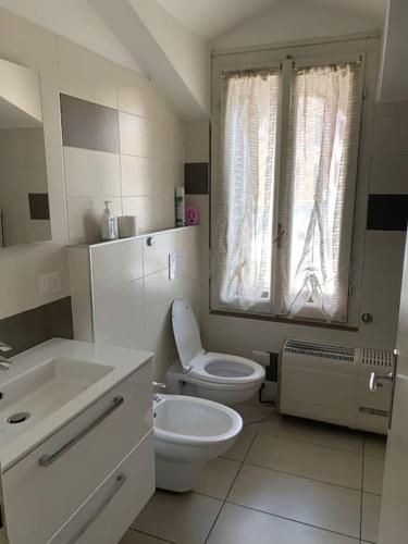 uma casa de banho branca com um WC e um lavatório em Casa Rino: Vacanze in casetta...... em Dongo