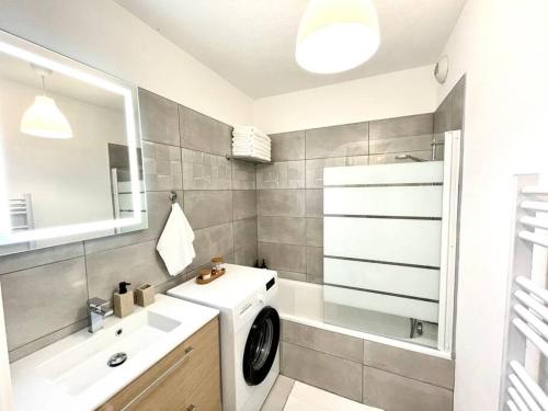 une salle de bain avec une machine à laver et un lavabo dans l'établissement L’attique - Standing et Terrasse au centre-ville, à Bellegarde-sur-Valserine