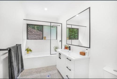 uma casa de banho com uma banheira, um lavatório e um espelho. em Tranquil paradise - whole home - with views! King and Queen beds em Woree