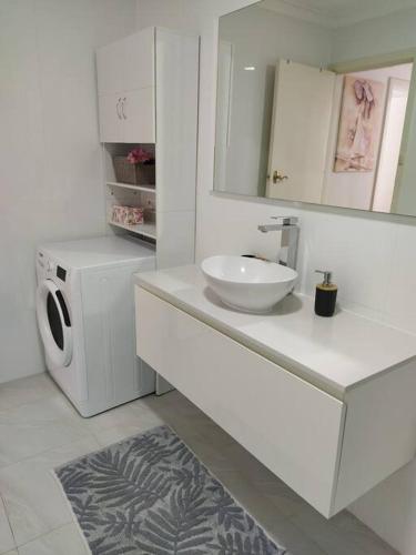 a bathroom with a sink and a washing machine at Modern Unit Near CBD & Beach, Free Parking in Perth