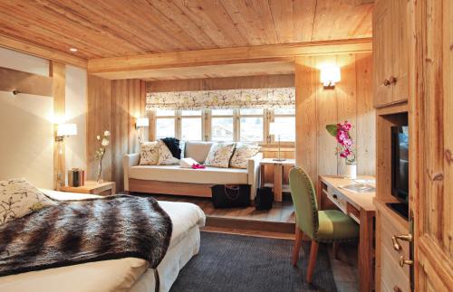 a bedroom with a bed and a couch in a room at Hôtel Les Peupliers in Courchevel