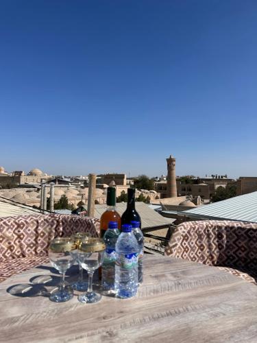 een tafel met wijnflessen en glazen op een balkon bij Abuzar in Bukhara