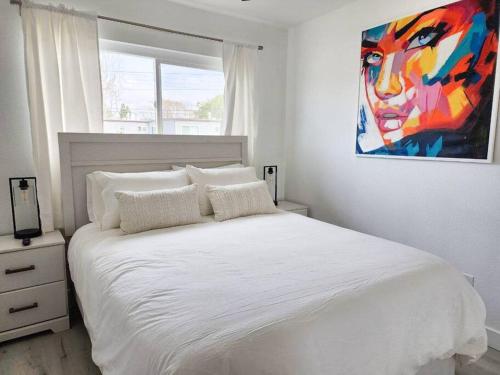 - une chambre avec un lit blanc orné d'une peinture murale dans l'établissement Stylish SD Living (10 min drive to Downtown and 15 min to beach), à Chula Vista