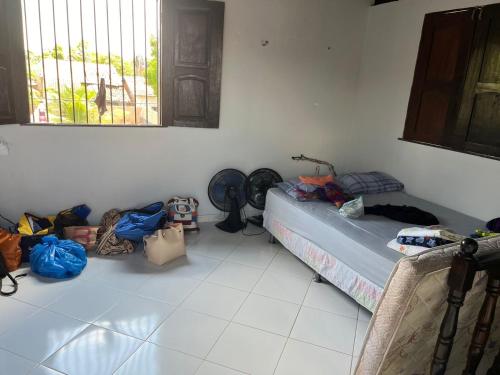 Zimmer mit einem Bett und Taschen sowie einem Fenster in der Unterkunft Chalé meu príncipe in Marapanim