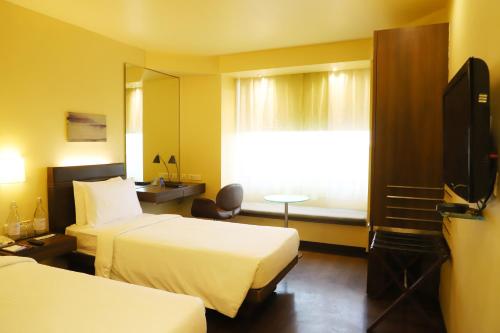 a hotel room with two beds and a television at Marasa Sarovar Portico -Rajkot in Rajkot