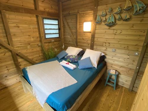 ein Schlafzimmer mit einem Bett in einem Blockhaus in der Unterkunft Kaz ananas, spa privatif ,plage du Helleux in Sainte-Anne
