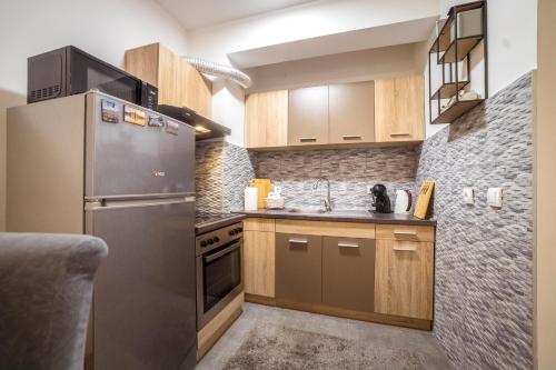 a kitchen with a stainless steel refrigerator and wooden cabinets at Lux Apartmani Rakić in Pirot