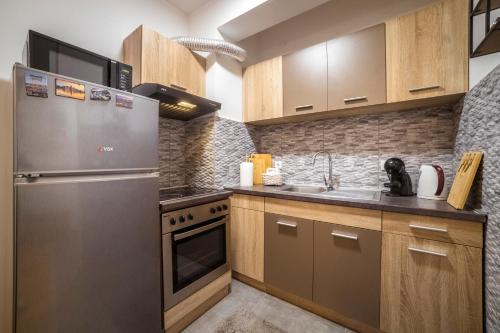 a kitchen with a stainless steel refrigerator and wooden cabinets at Lux Apartmani Rakić in Pirot