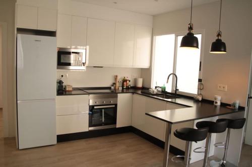 une cuisine avec des placards blancs et un comptoir noir dans l'établissement Ca Lanosa, à Alicante