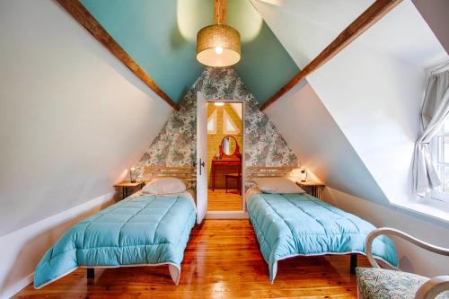 - deux lits dans une chambre mansardée avec un toit dans l'établissement La Longère Beauséjour, à Canapville